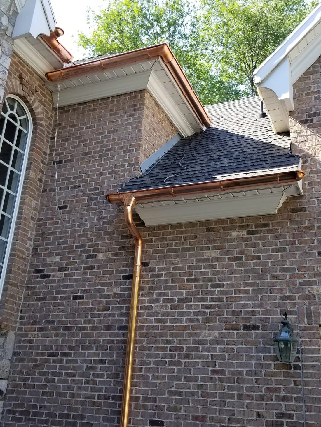 Copper gutter and downspout installed by Betty’s Best on a brick home
