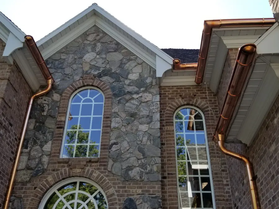 Stone and brick home with copper gutters and round copper downspouts