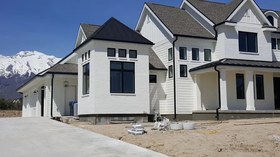 White modern farmhouse with black seamless gutters and snowy mountains behind